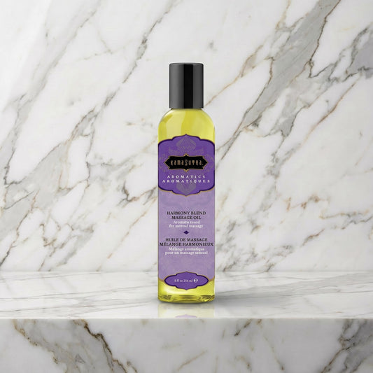 Fles Harmony Blend massageolie met paars etiket op een marmeren plank, Kama Sutra