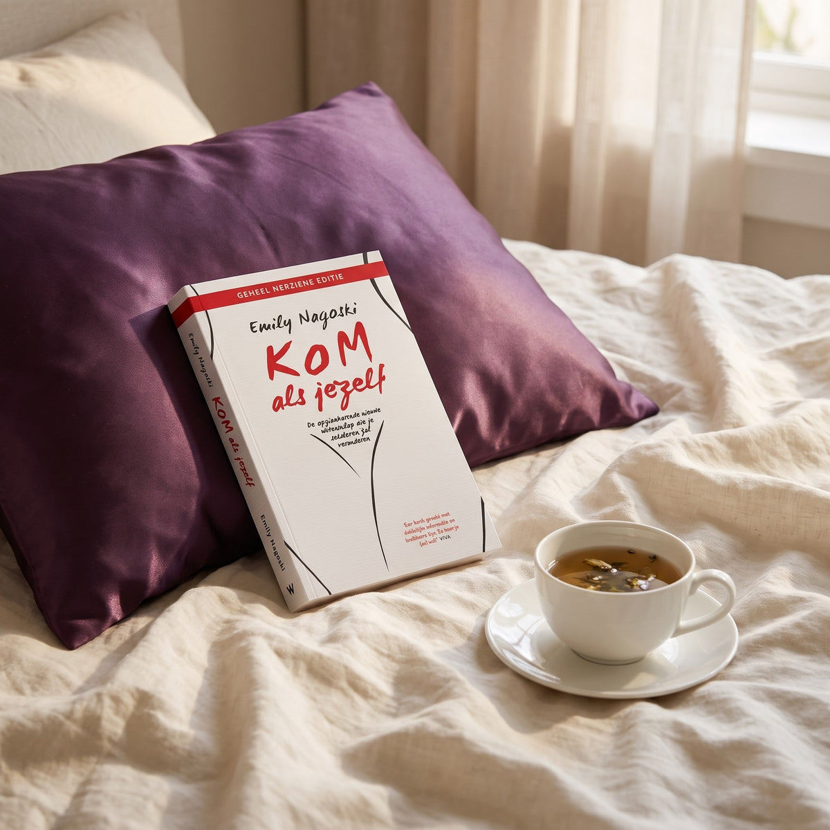 Sfeerbeeld: het boek Kom als jezelf van Emily Nagoski op een bed met een kop thee