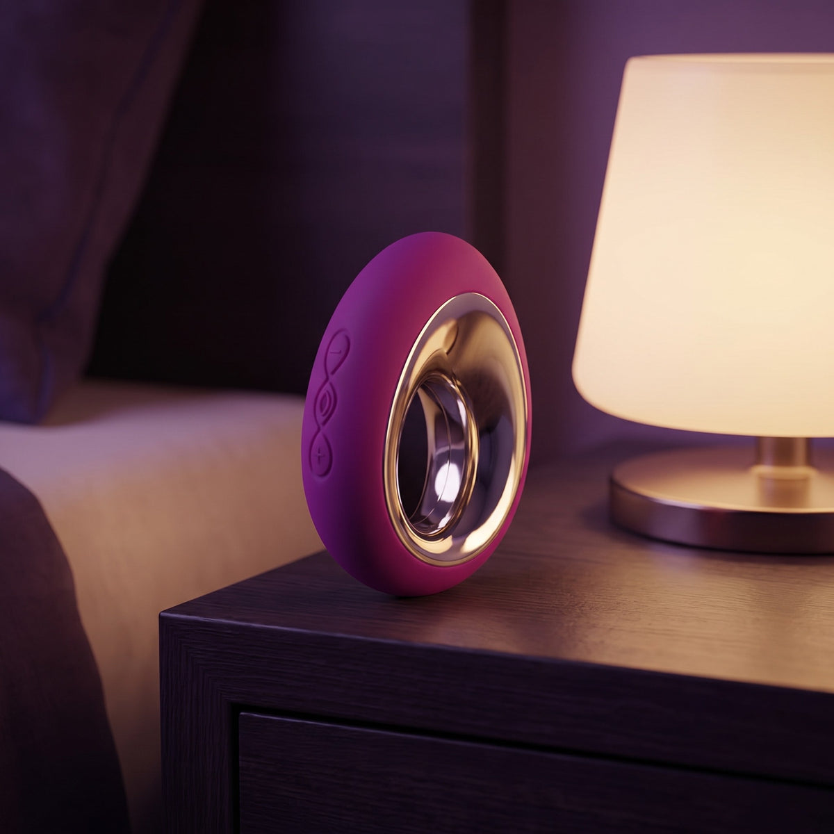 Sfeerbeeld: paarse LELO Alia op een nachtkastje naast een brandende lamp in avondlicht