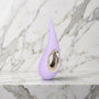 Lila druppelvormige vibrator met gouden ring op een marmeren plank, LELO Dot in lavendel