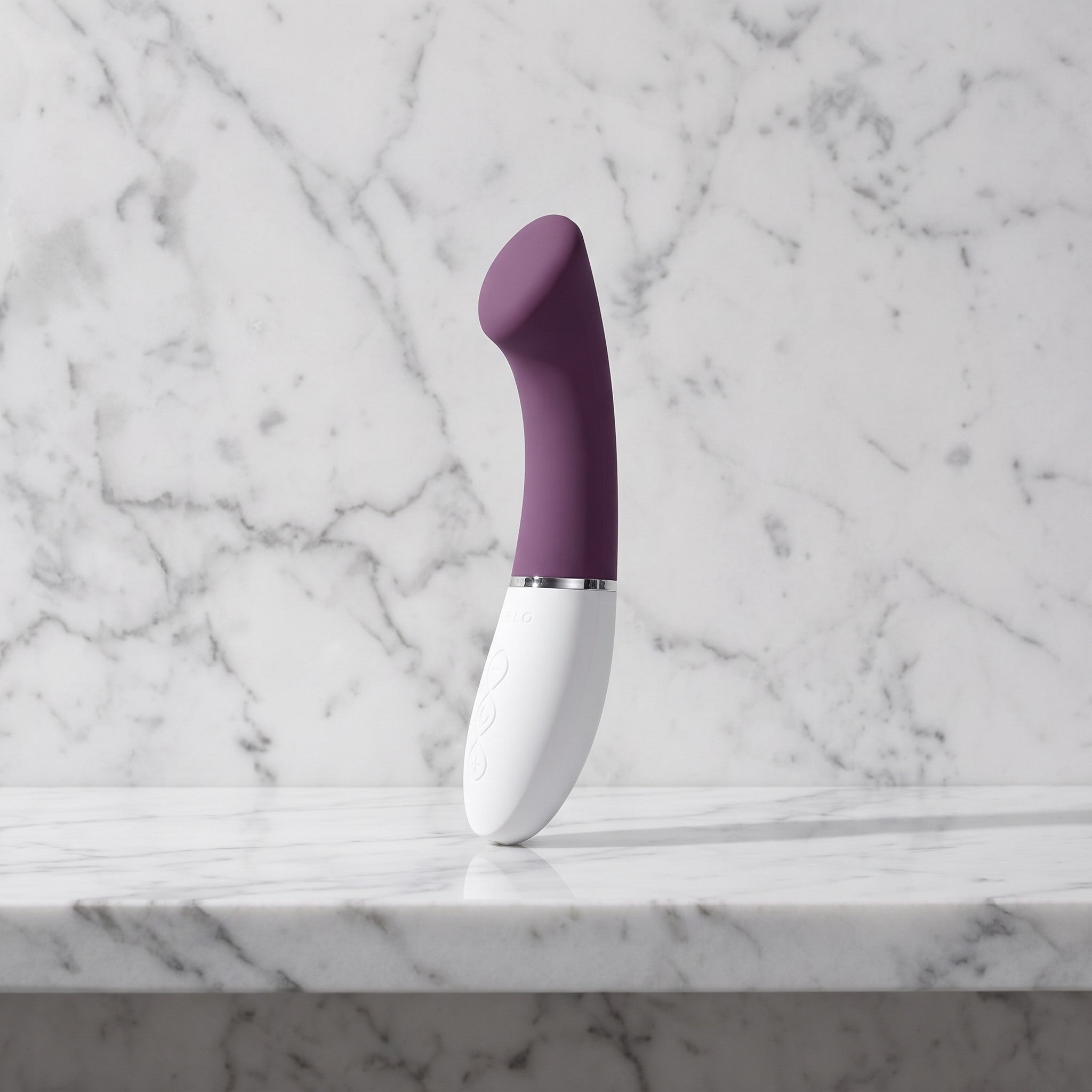 LELO Gigi 3 in plum met witte handgreep, G-spotvibrator met afgeplatte top, op een marmeren plank