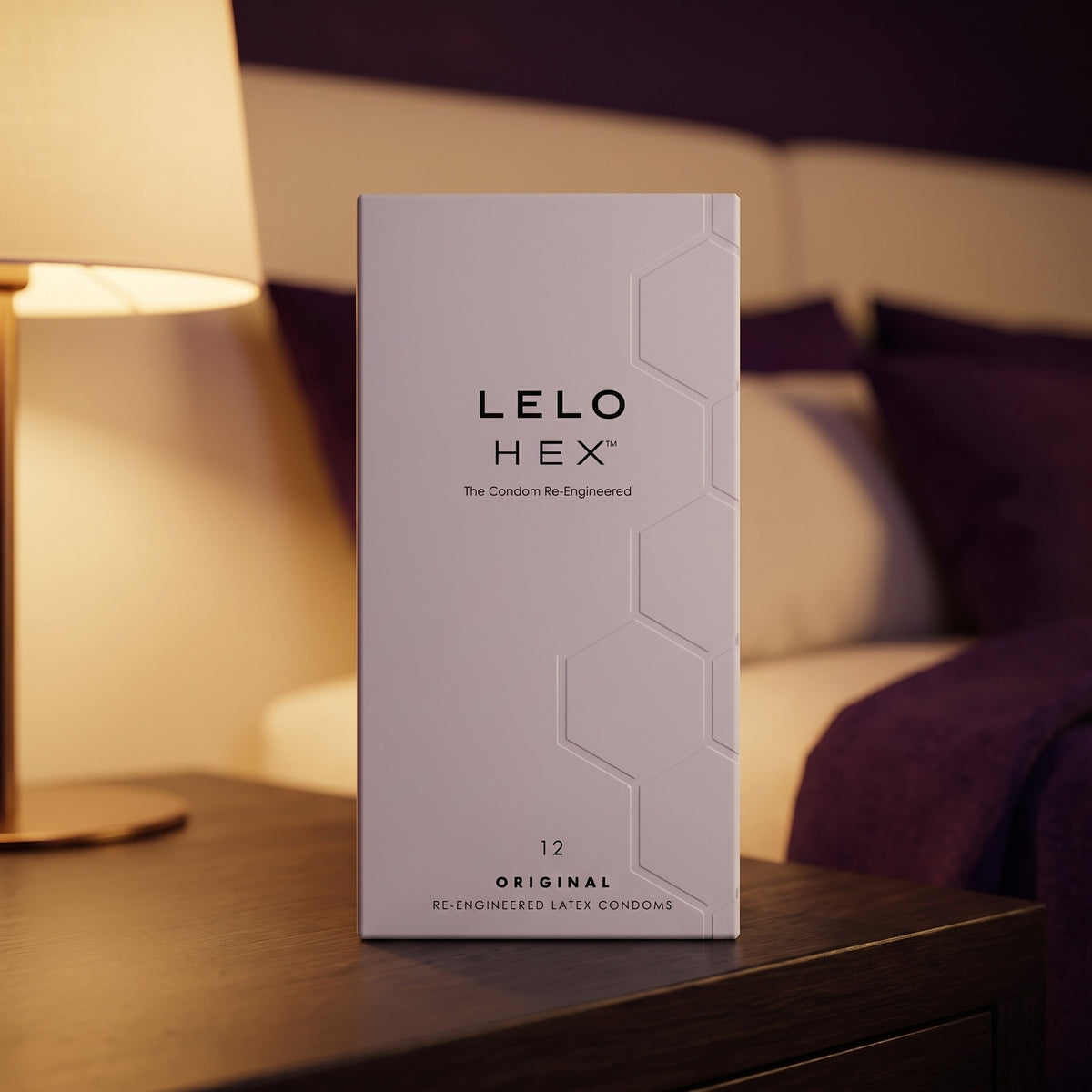 Sfeerbeeld: witte doos LELO HEX condooms op een nachtkastje naast een brandende lamp