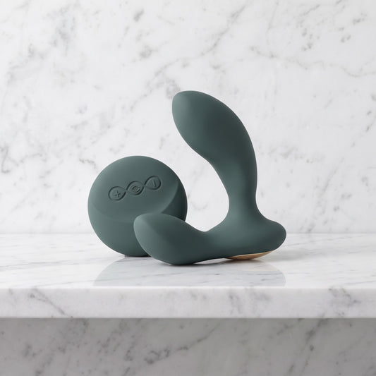 Groene LELO Hugo 2 Remote prostaatmassager met ronde afstandsbediening, op een marmeren plank