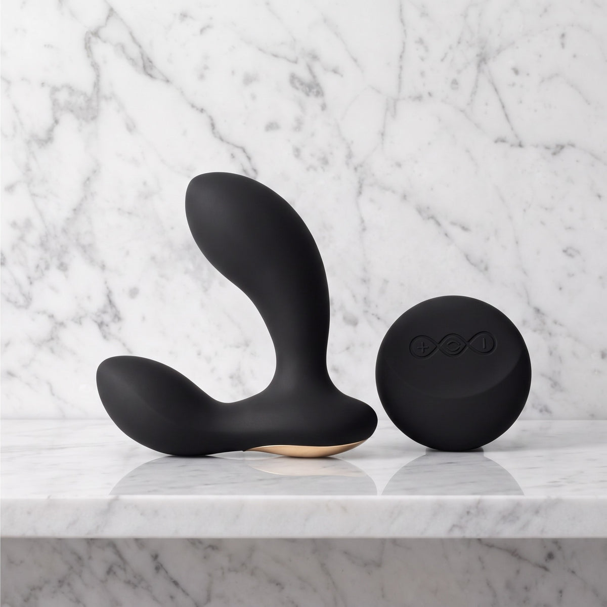 Zwarte LELO Hugo 2 Remote prostaatmassager met ronde afstandsbediening, op een marmeren plank