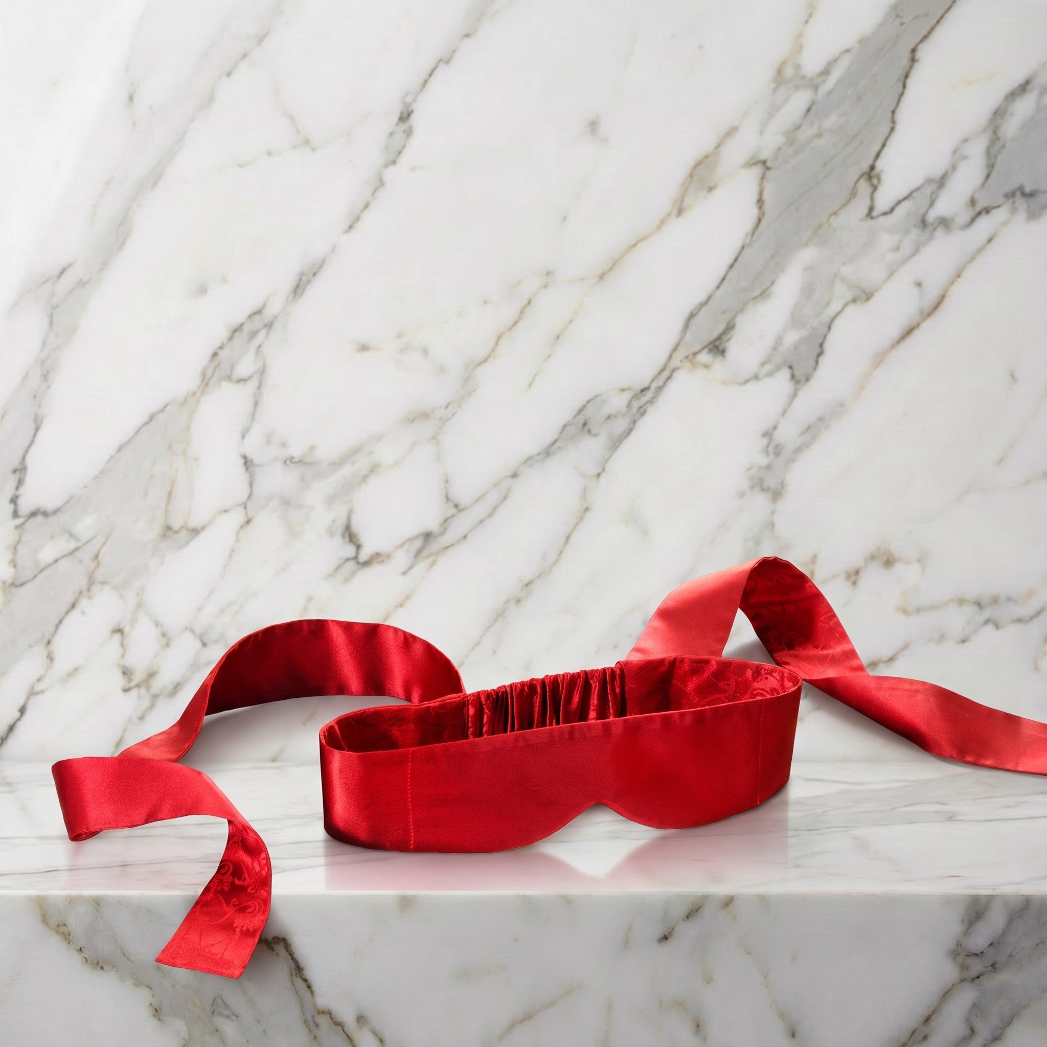 Rode zijden blinddoek met twee lange linten op een marmeren plank, Lelo Intima Silk
