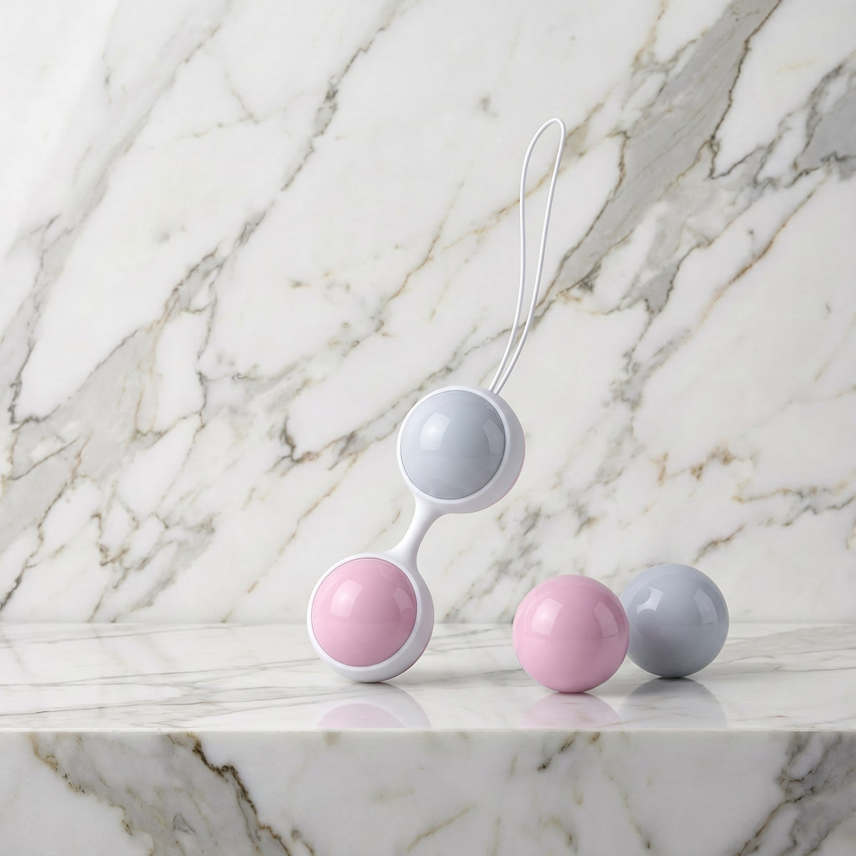 Vier roze en blauwe kegelballen met witte houder op een marmeren plank, Luna Beads Mini van LELO