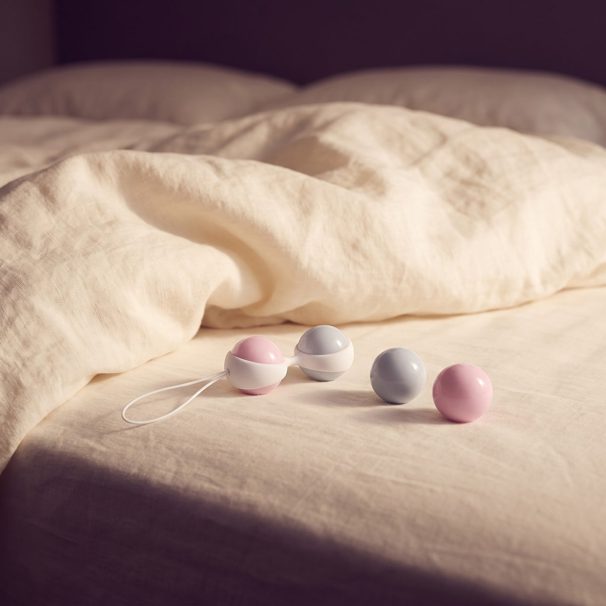 Sfeerbeeld: Luna Beads Mini kegelballen op een opgemaakt bed met creme linnen in ochtendlicht