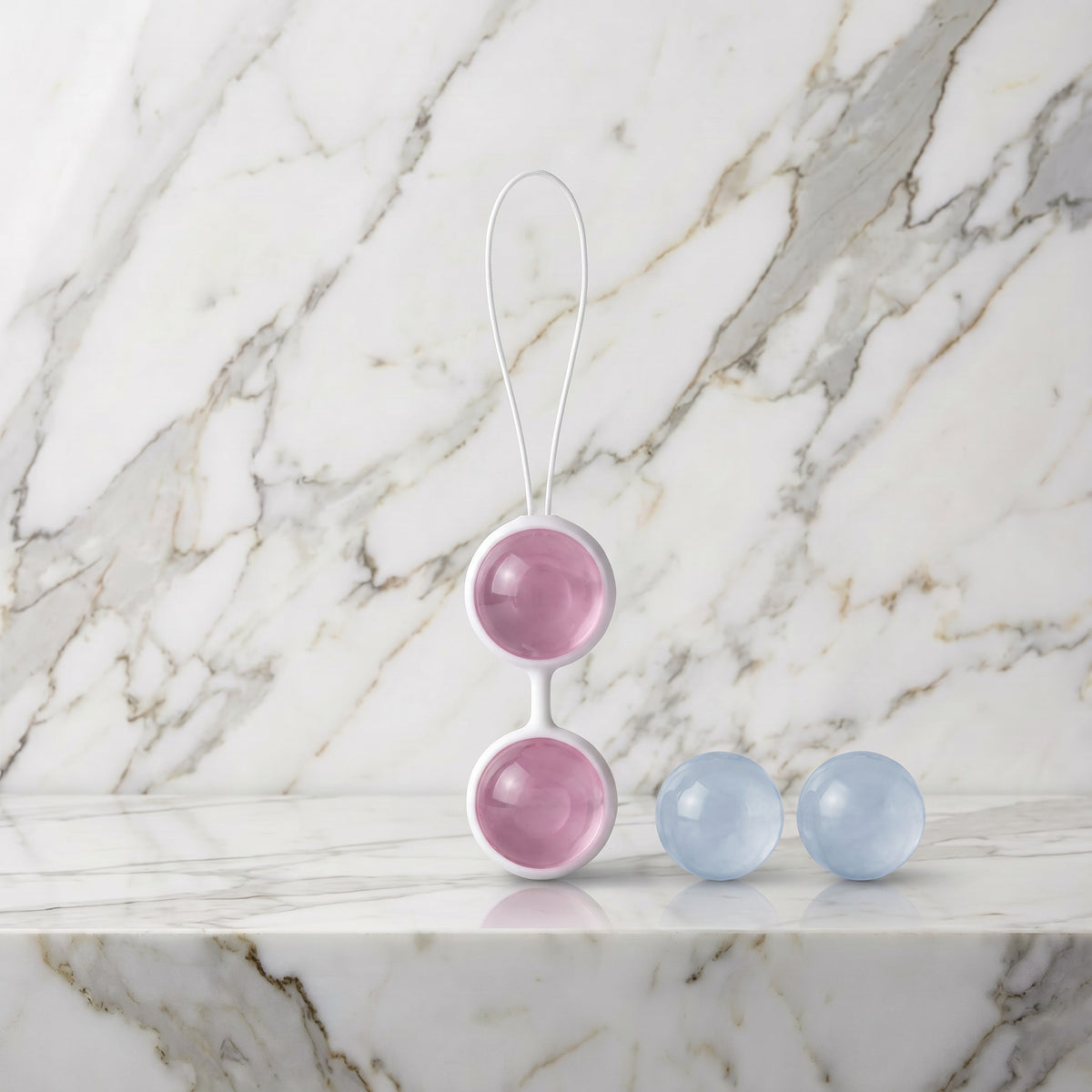 LELO Luna Beads met wit harnas en roze en blauwe balletjes op een marmeren plank