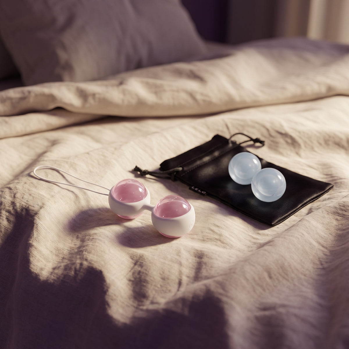Sfeerbeeld: LELO Luna Beads op een opgemaakt bed met creme linnen in ochtendlicht