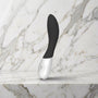 Zwarte Mona Wave vibrator met wit handvat op een marmeren plank, Lelo