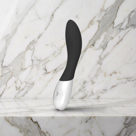 Zwarte Mona Wave vibrator met wit handvat op een marmeren plank, Lelo