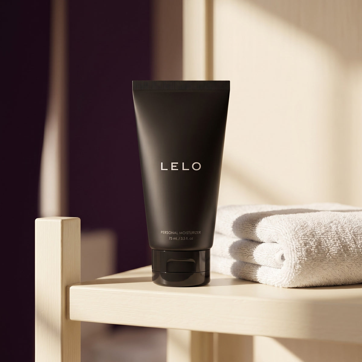Sfeerbeeld: zwarte LELO Personal Moisturizer tube op een badkamerplank naast een handdoek