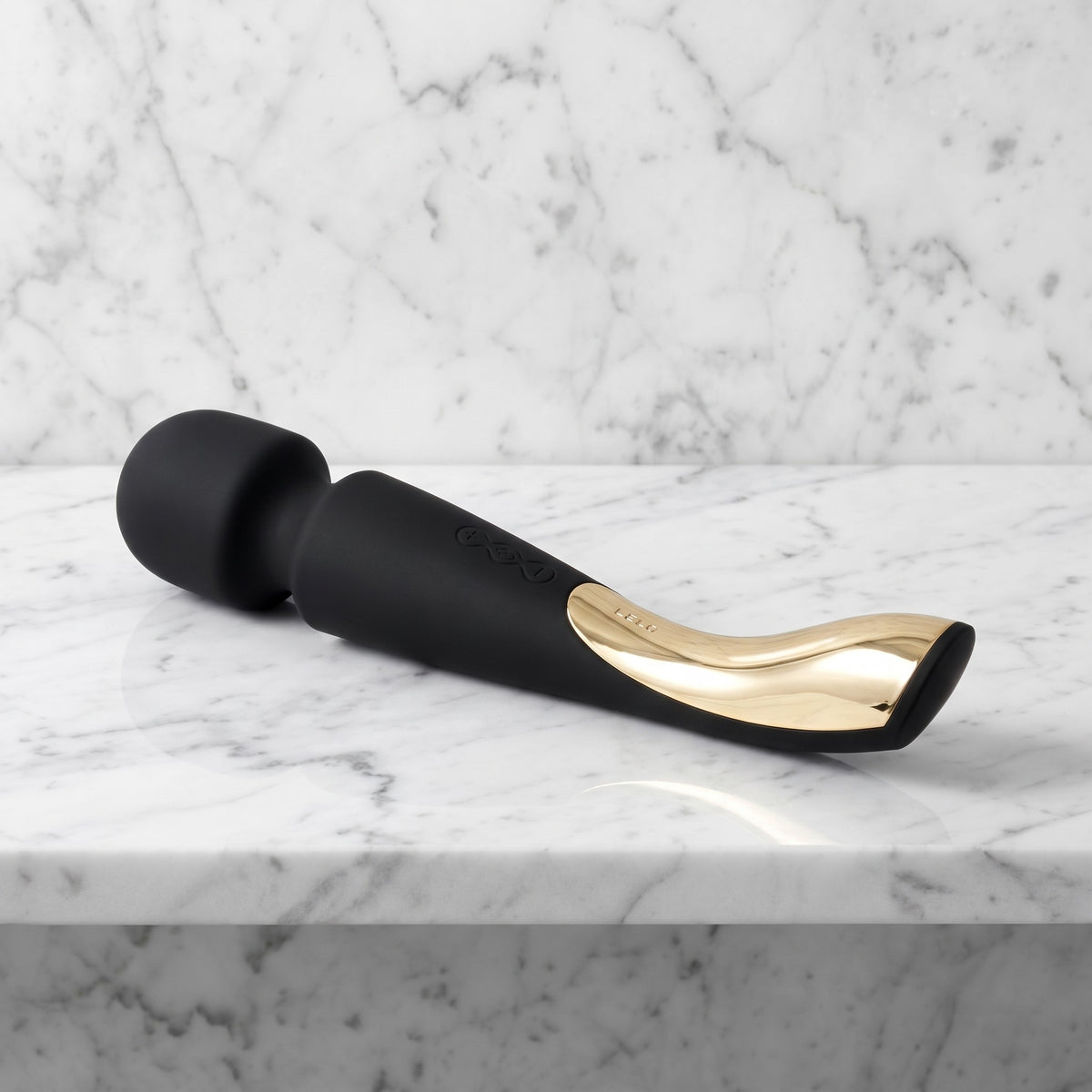 LELO Smart Wand 2 Medium in zwart met gouden handgreep, liggend op een marmeren plank