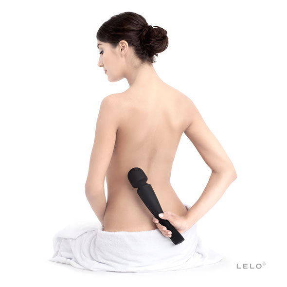 Vrouw masseert haar onderrug met de zwarte Smart Wand Large 2 van Lelo
