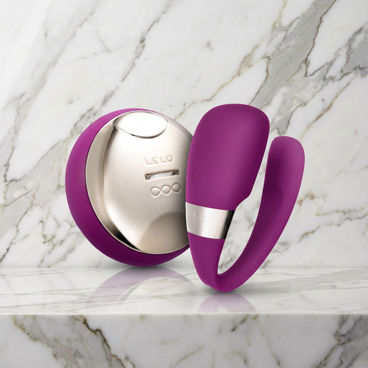 Paarse Tiani 3 koppelvibrator met afstandsbediening op een marmeren plank, LELO