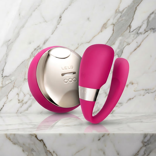 Roze-rode Tiani 3 koppelvibrator met afstandsbediening op een marmeren plank, LELO