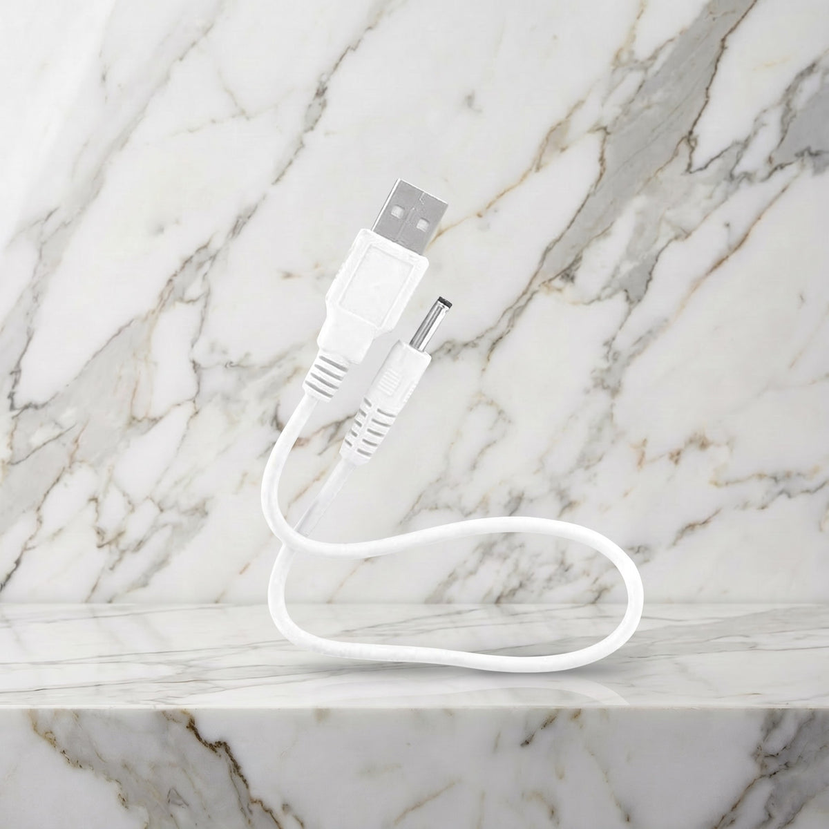 Witte USB-oplaadkabel met ronde pin op een marmeren plank, LELO oplader