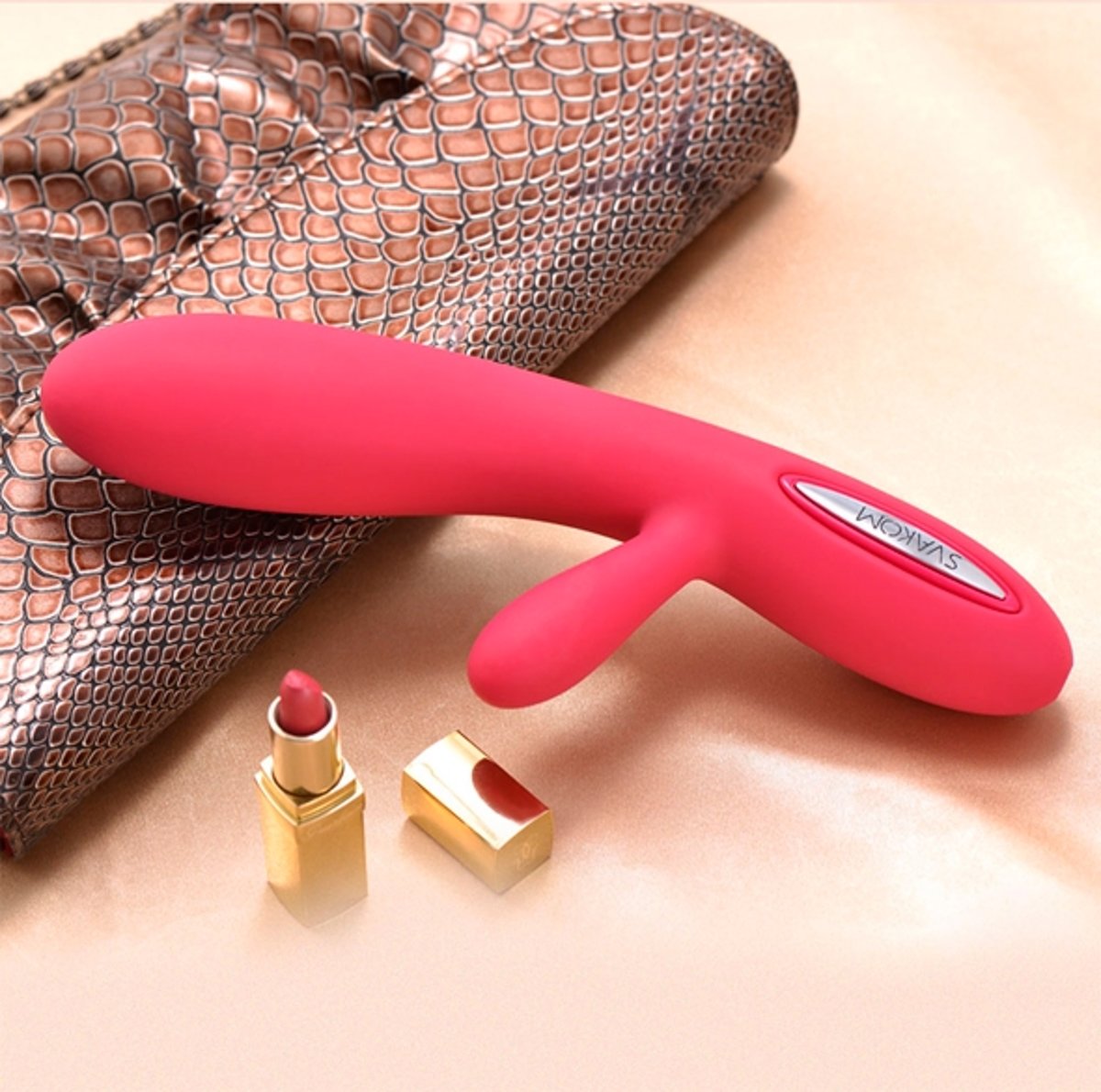 Sfeerbeeld: roze Lester rabbit vibrator op een glanzend slangenleren tasje naast een gouden lippenstift