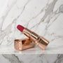 Lippenstift vibrator met roségouden huls en rood topje op een marmeren plank