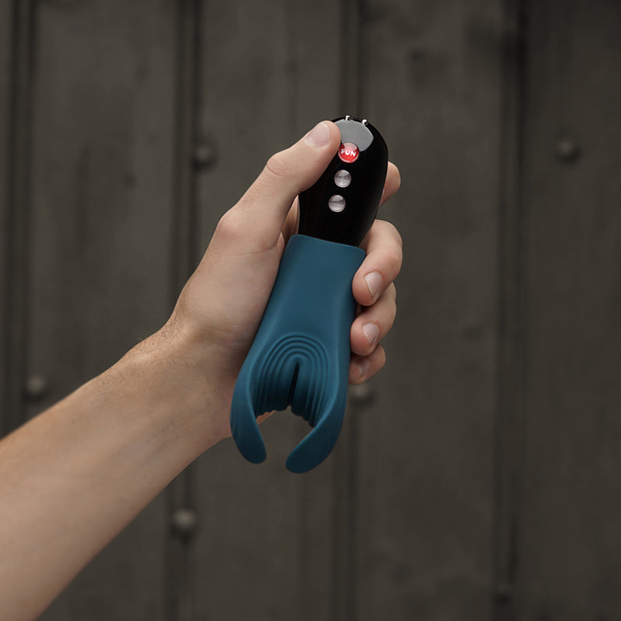 Fun Factory Manta vibrating stroker in petrolblauw vastgehouden in een hand