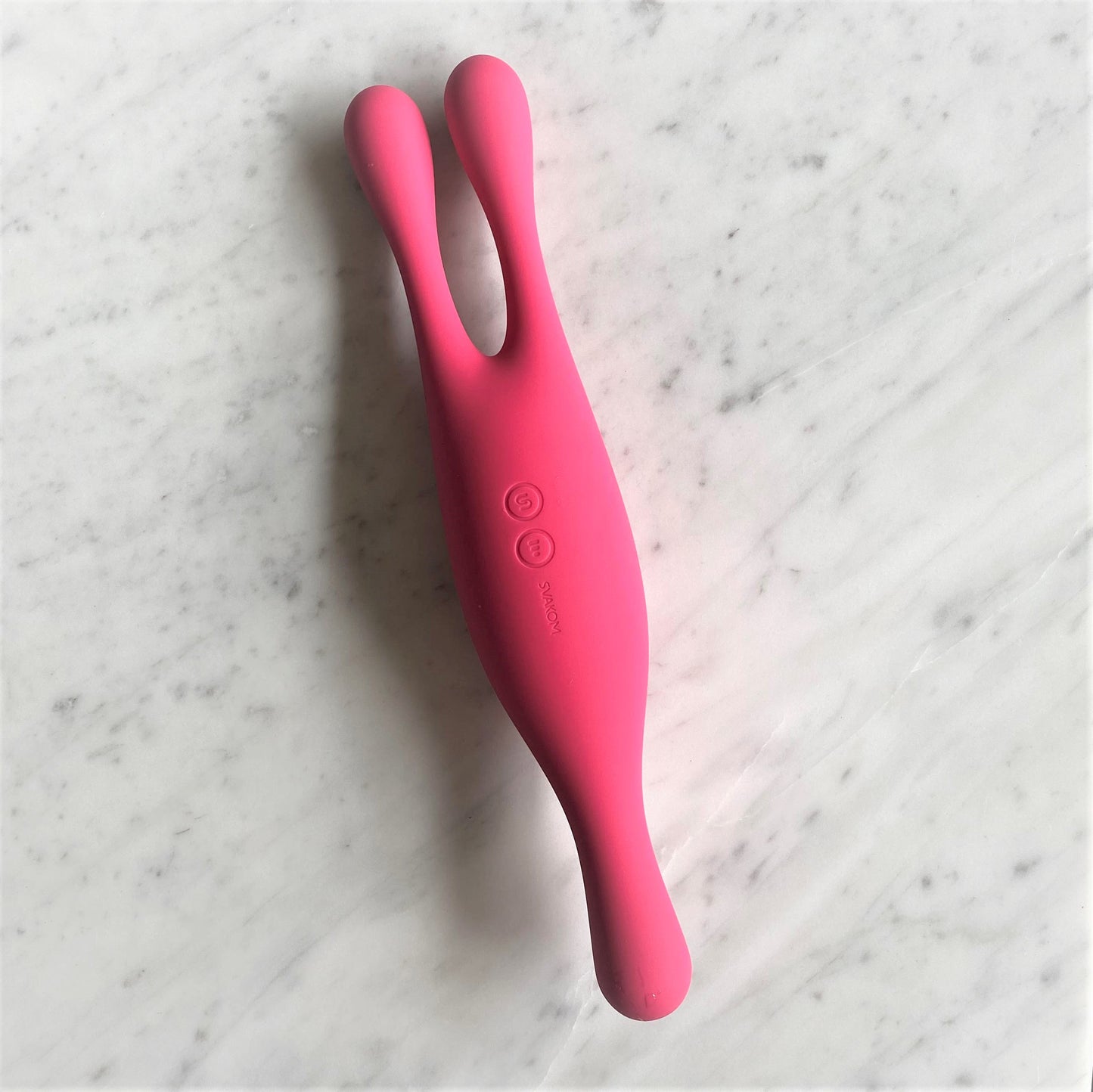 Svakom Marin vibrator in roze op marmeren ondergrond met bedieningsknoppen zichtbaar
