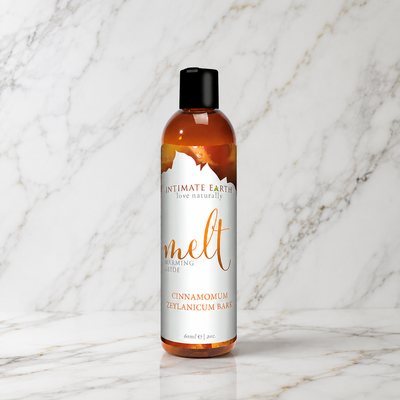 Flesje Intimate Earth Melt verwarmend glijmiddel rechtop op een marmeren plank