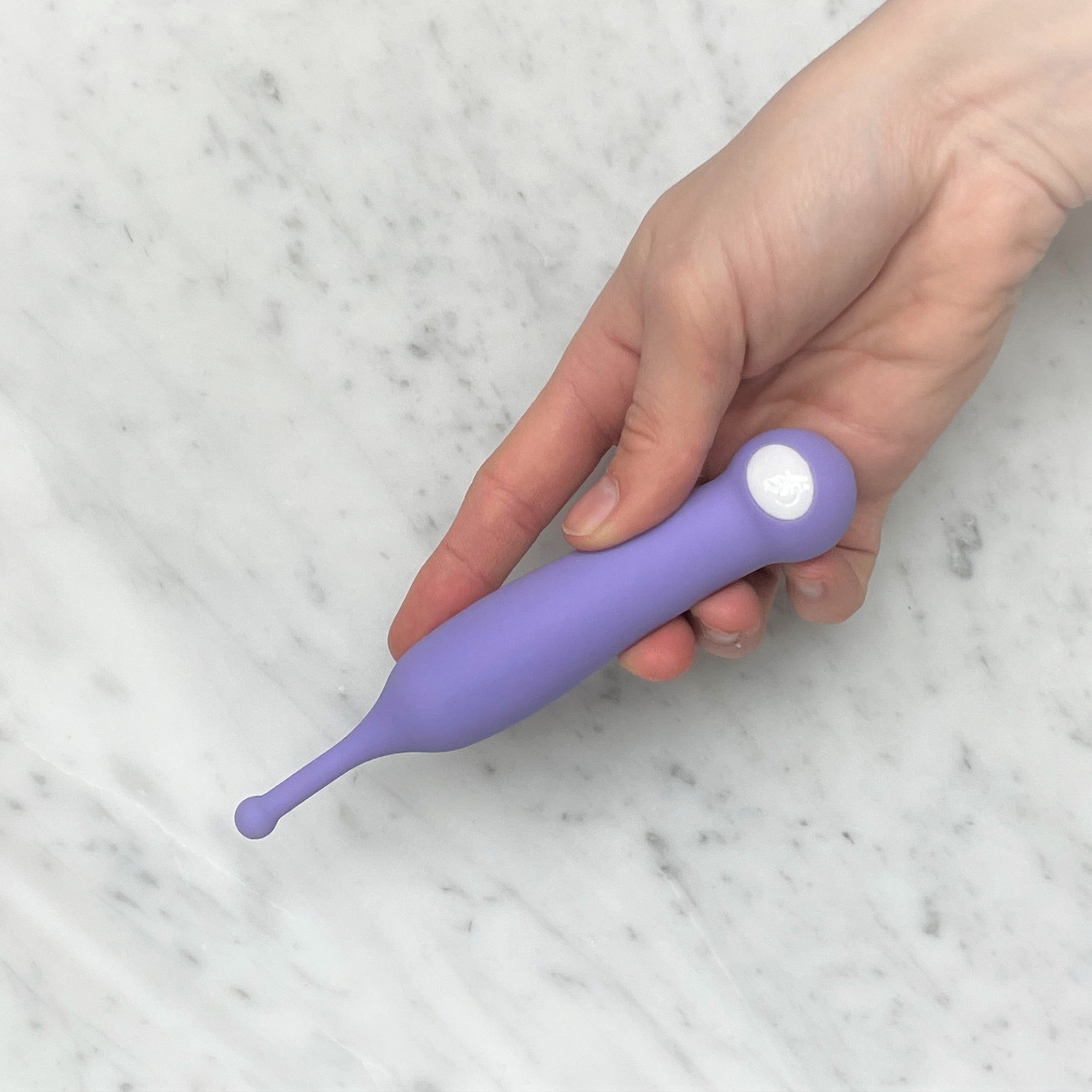 Lila clitoris vibrator met precisiepunt in hand, siliconen materiaal, zijaanzicht marmeren achtergrond
