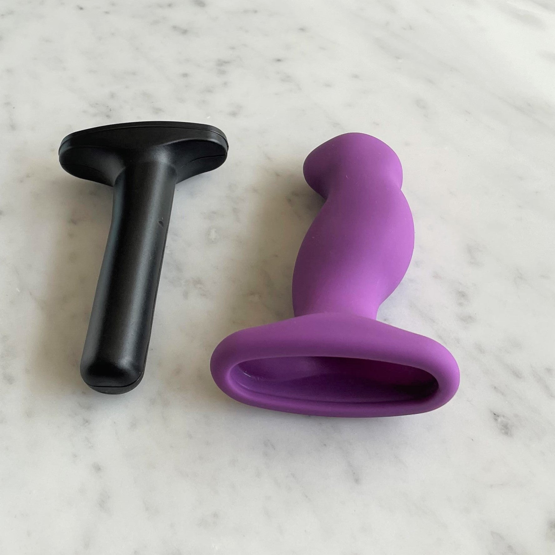 Nexus G-Play+ Medium met de losse paarse siliconen huls naast de zwarte bullet, op marmer