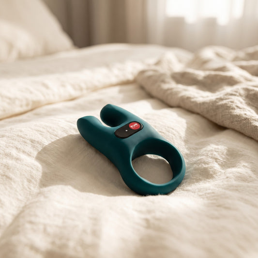 Sfeerbeeld van de groene NOS vibrerende cockring liggend op creme linnen op bed, Fun Factory