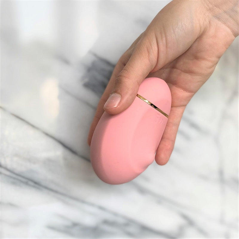 Ioba OhMyG roze siliconen lay-on vibrator met gouden sierrand vastgehouden in hand, zijaanzicht