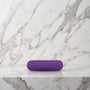 Paarse oplaadbare bullet vibrator liggend op een marmeren plank