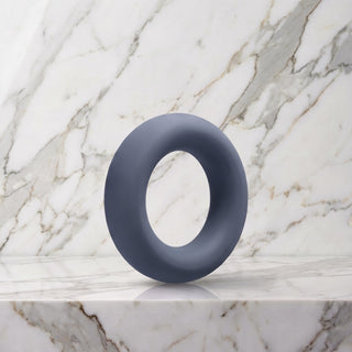 Brede leigrijze siliconen cockring van 35 mm op een marmeren plank, OptiMALE C-Ring
