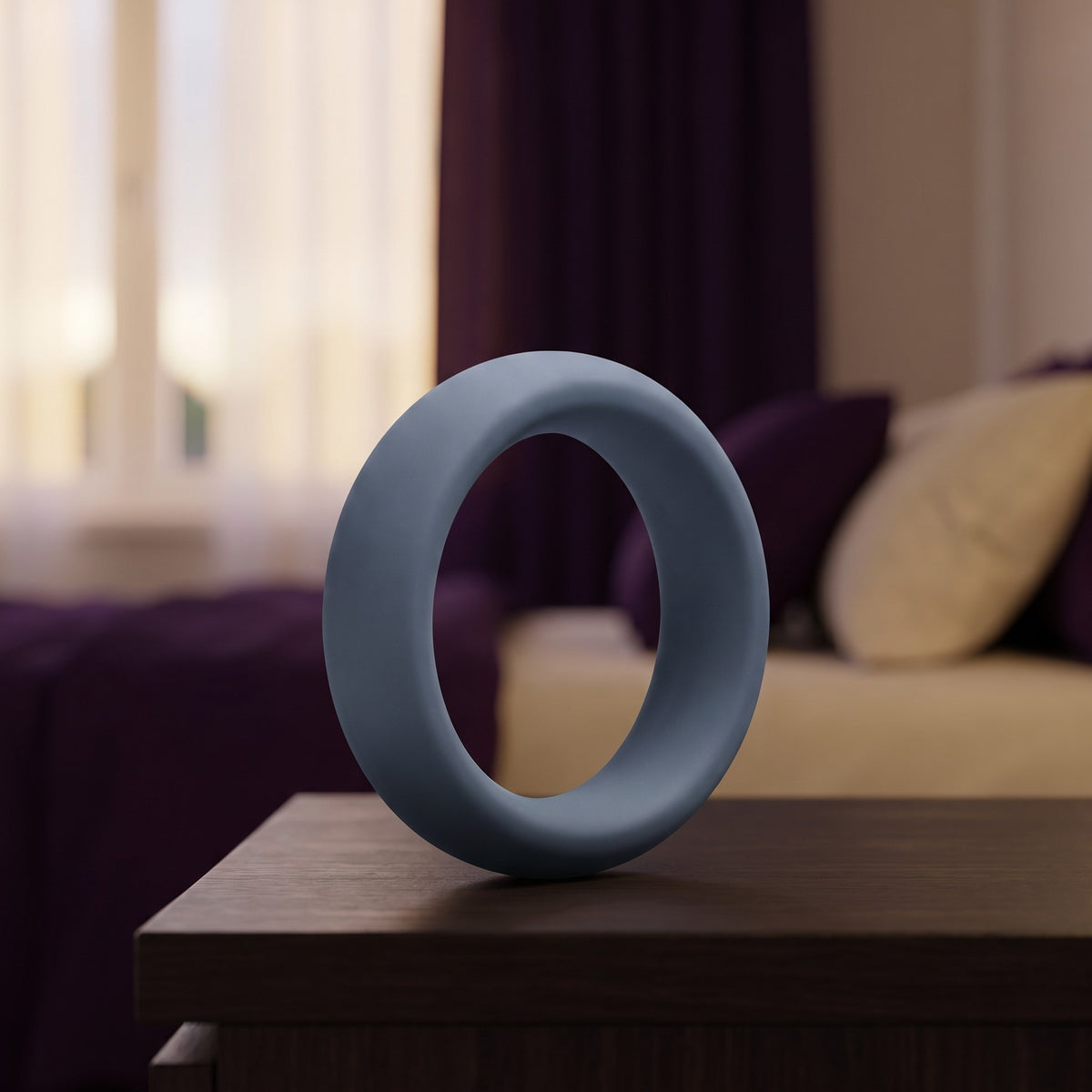 Sfeerbeeld: leigrijze cockring van 40 mm op een houten nachtkastje in een slaapkamer