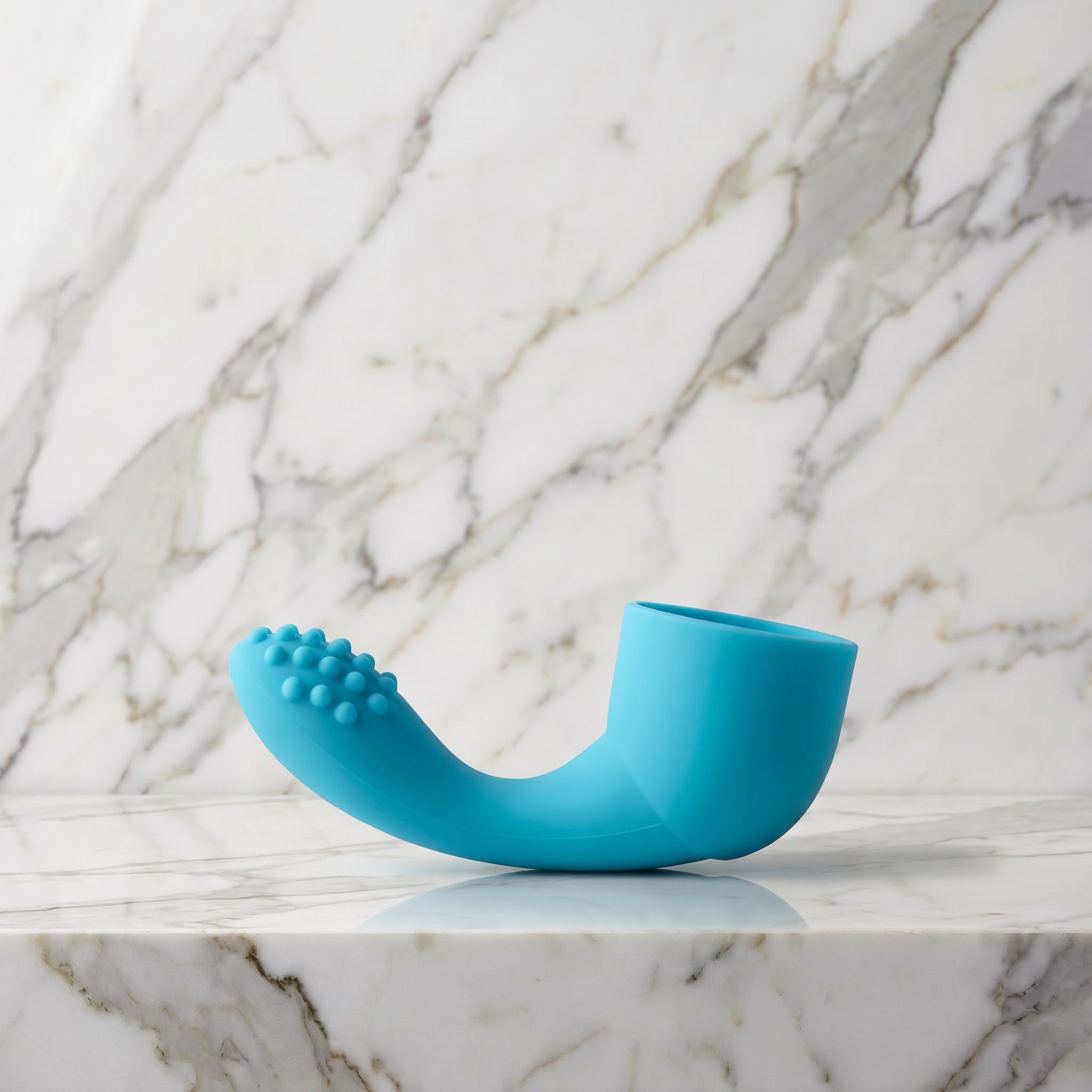 Aqua blauw siliconen opzetstuk voor een wandmassager liggend op een marmeren plank