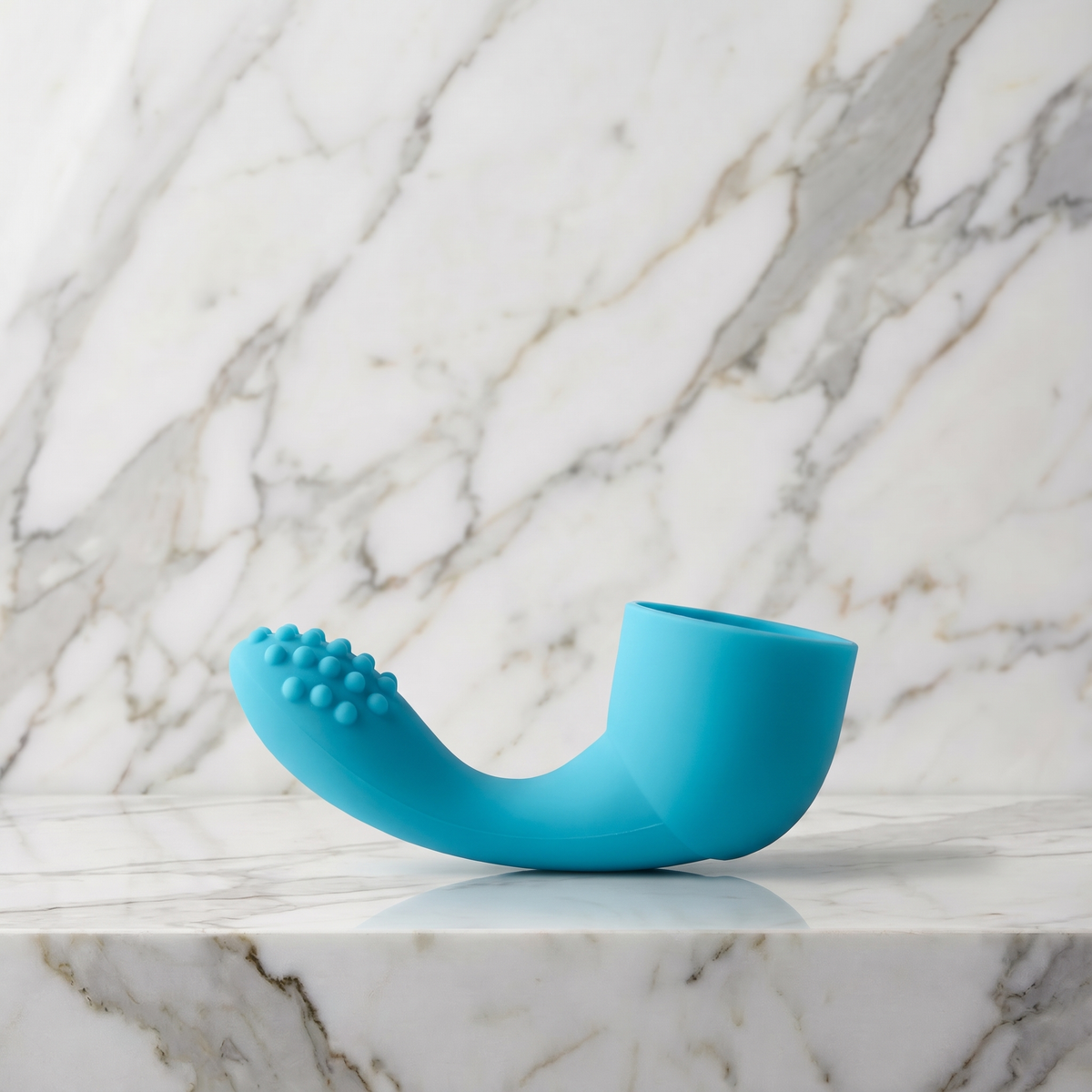 Aqua blauw siliconen opzetstuk voor een wandmassager liggend op een marmeren plank