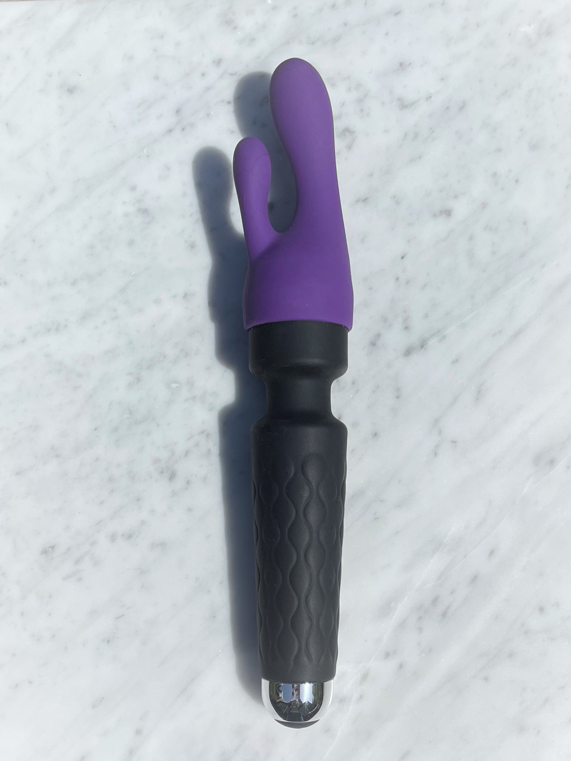 Paars rabbit-opzetstuk op de zwarte Super wand massager klein formaat, liggend op marmer