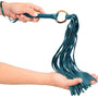 Groene flogger in de hand, de strengen vallen over een open handpalm en tonen de lengte