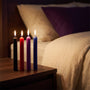 Sfeerbeeld: vier brandende kaarsjes voor wax play op een nachtkastje bij warm licht