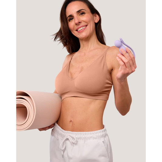 Lachende vrouw met een yogamat onder de arm houdt de lila trainer omhoog, Perifit Care+