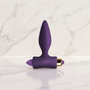 Paarse buttplug met gouden bullet rechtop op een marmeren plank, Petite Sensations Plug in paars