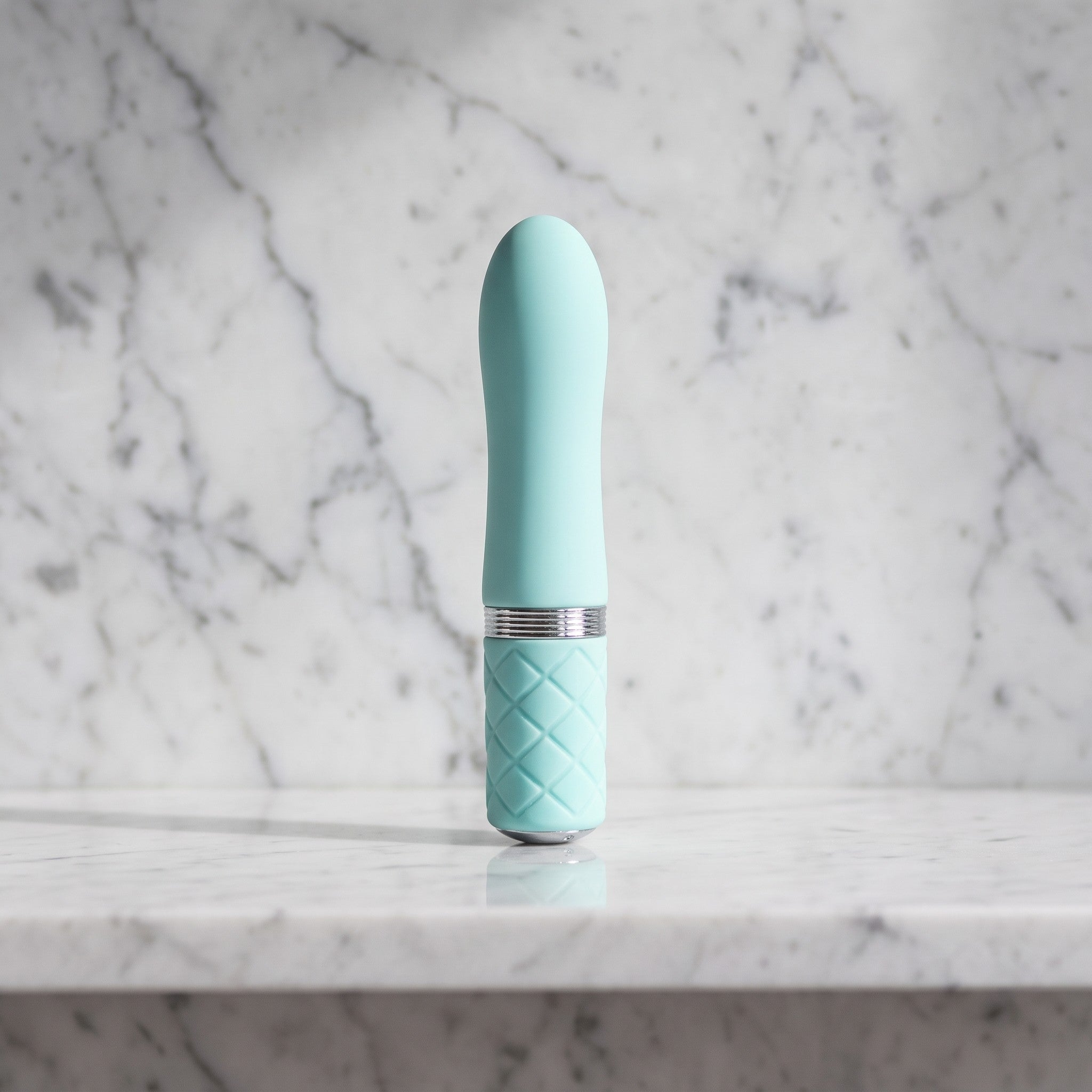 Licht blauwe mini vibrator met ruitjesgreep rechtop op een marmeren plank, Pillow Talk Flirty