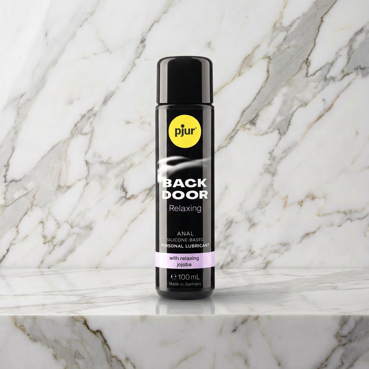 Zwarte fles Pjur Back Door Relaxing anaal glijmiddel van 100 ml op een marmeren plank