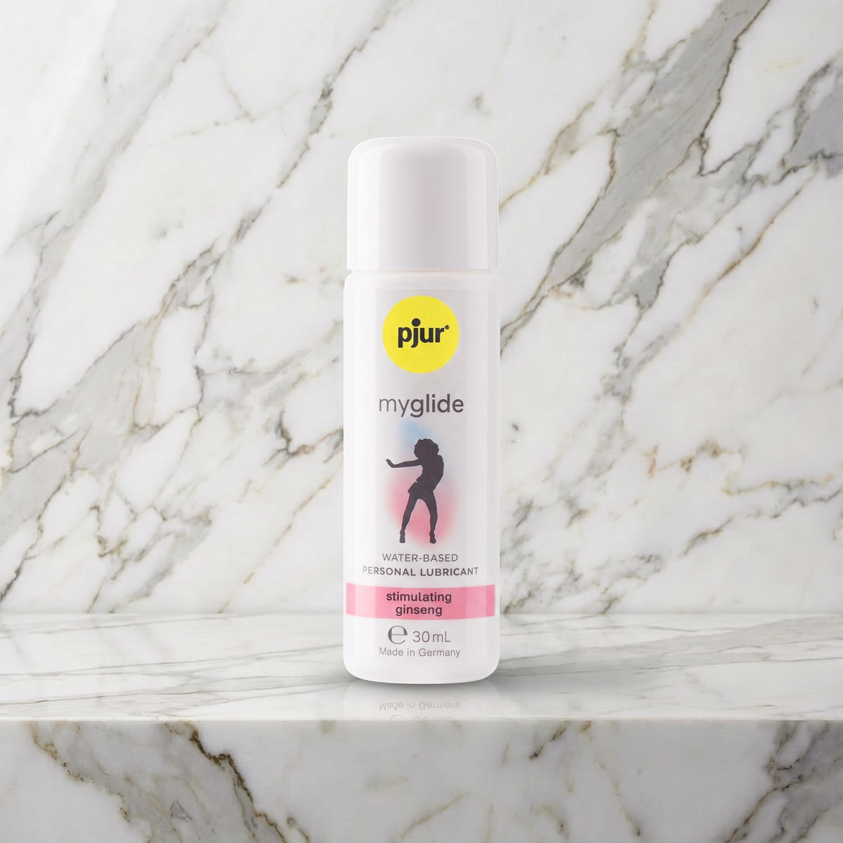 Wit flesje glijmiddel met geel logo en roze band op een marmeren plank, pjur myglide 30 ml