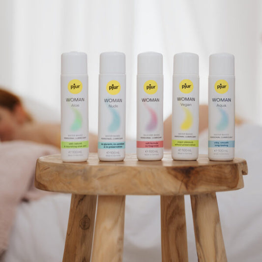 Pjur Woman collectie 5 flesjes 100 ml op houten krukje: Aloe, Nude, Woman, Vegan en Aqua varianten
