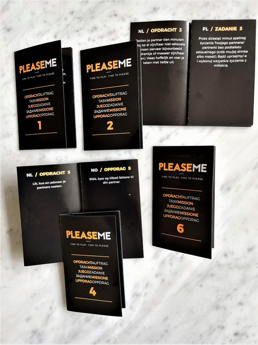 PleaseMe opdrachtkaarten uitgespreid op marmer, genummerd 1-6, zwart met oranje tekst