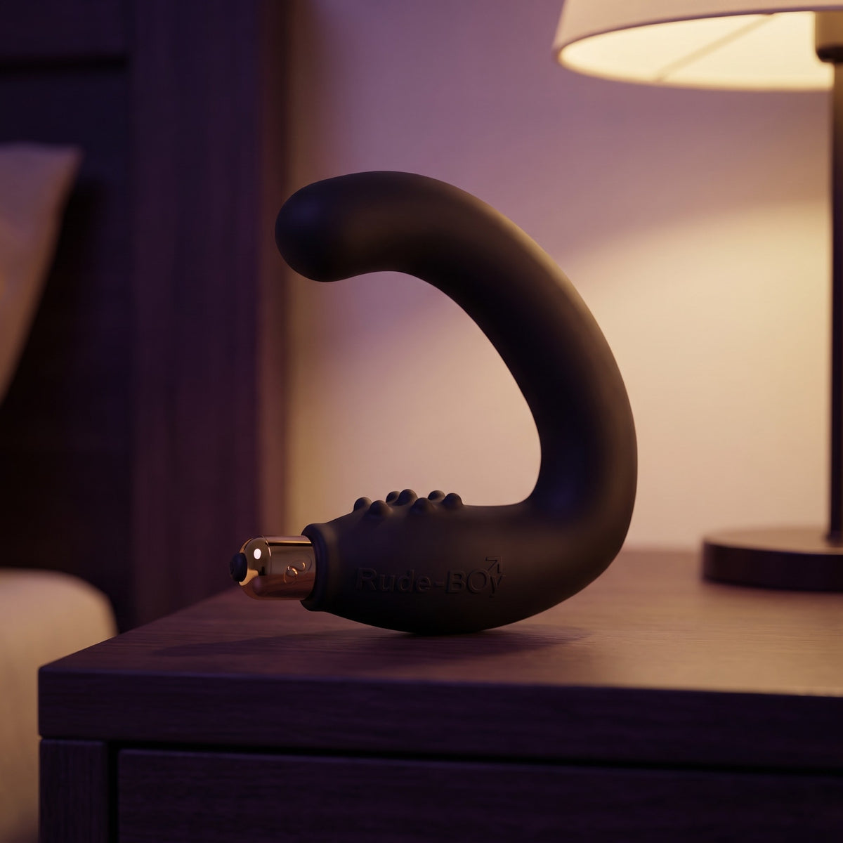 Sfeerbeeld: zwarte Rocks-Off Rude Boy op een nachtkastje naast een lamp in gedempt licht