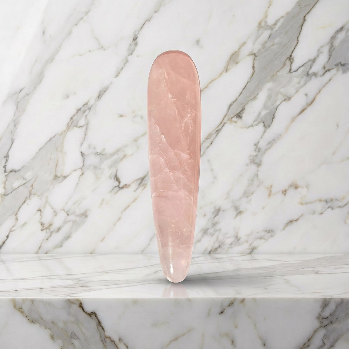 Rozenkwarts massage wand Large rechtop op een marmeren plank, zachtroze natuursteen