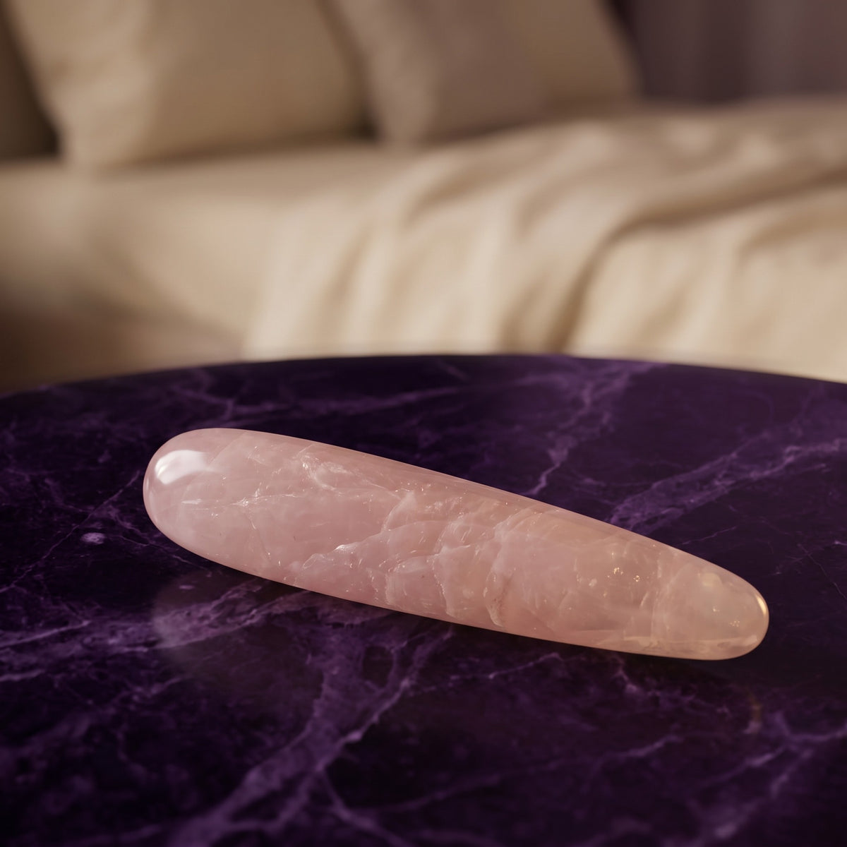 Sfeerbeeld: de rozenkwarts massage wand liggend op donkerpaars marmer in een slaapkamer