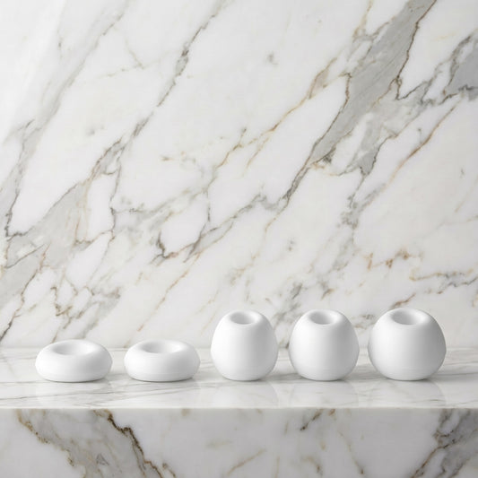 Vijf witte siliconen opzetstukken van de Satisfyer Caps Pro 2 op een marmeren plank