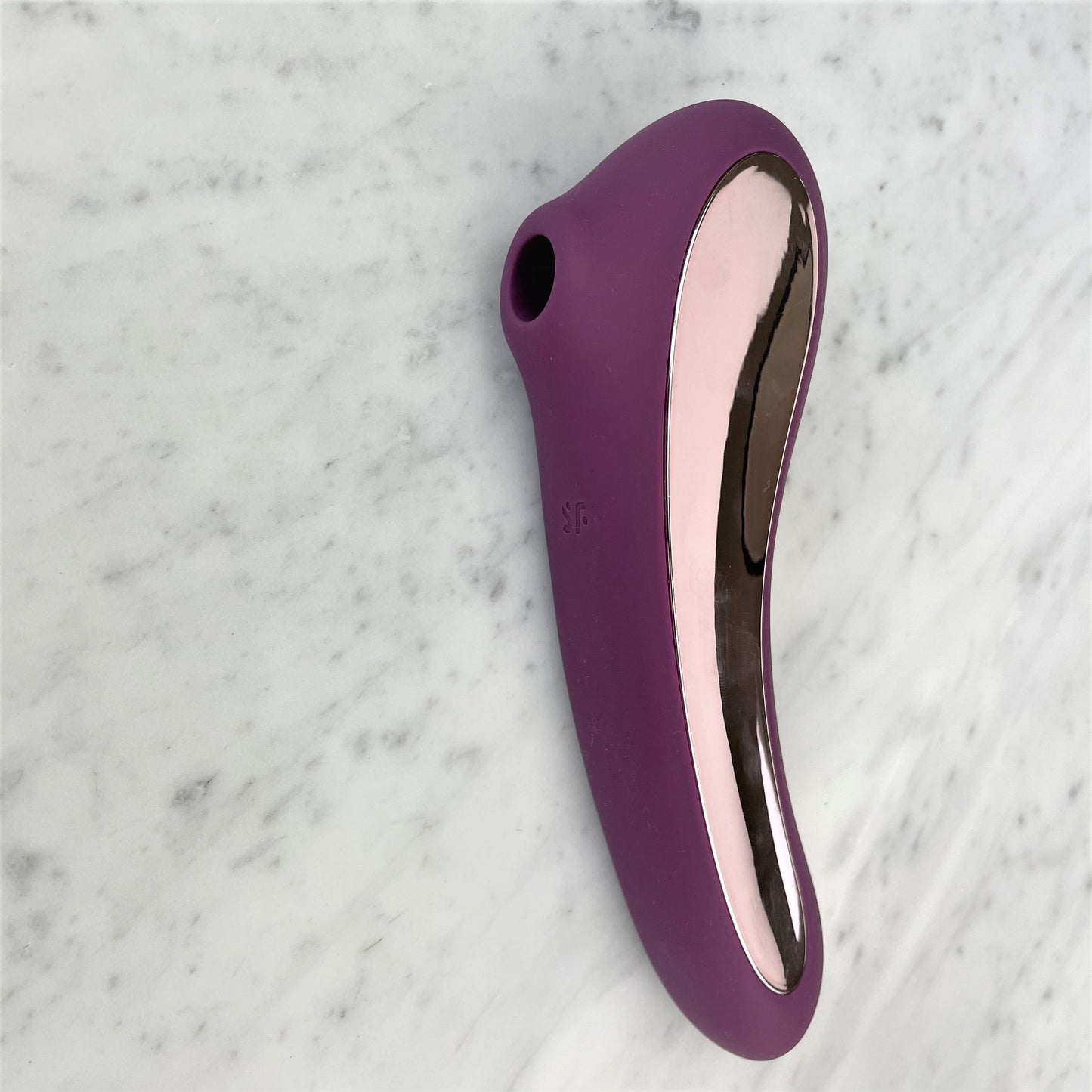 Paarse Satisfyer Dual Kiss luchtdrukstimulator met roségouden accent, bovenaanzicht op marmer